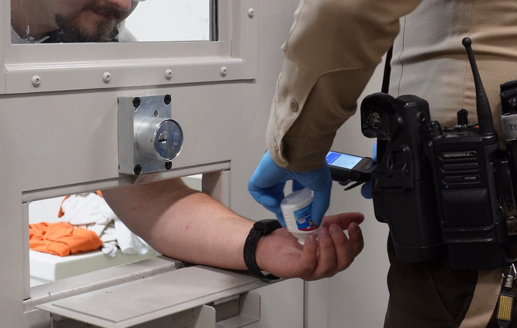 Correctional officer logging a med pass with a mobile device in our mobile RFID inmate tracking system